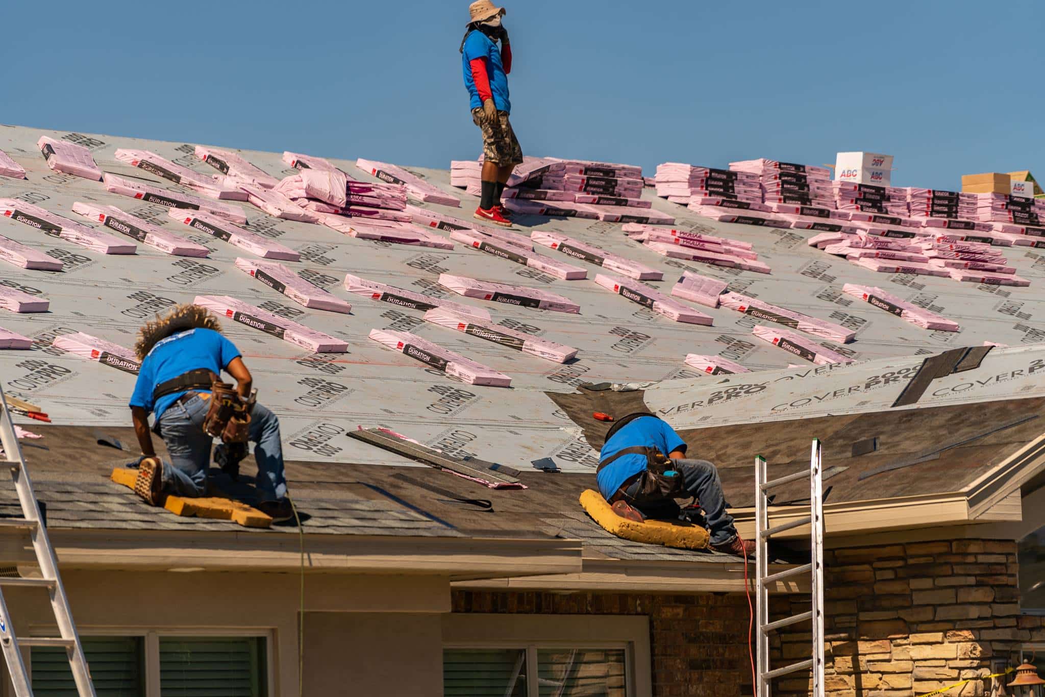 men laying shingles on roof